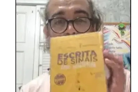 Hermeson segurando o livro Escrita de Sinais sem Mistérios no depoimento